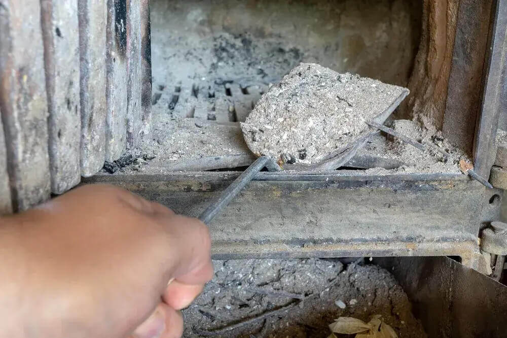 Osoba wyjmuje popiół z pieca
