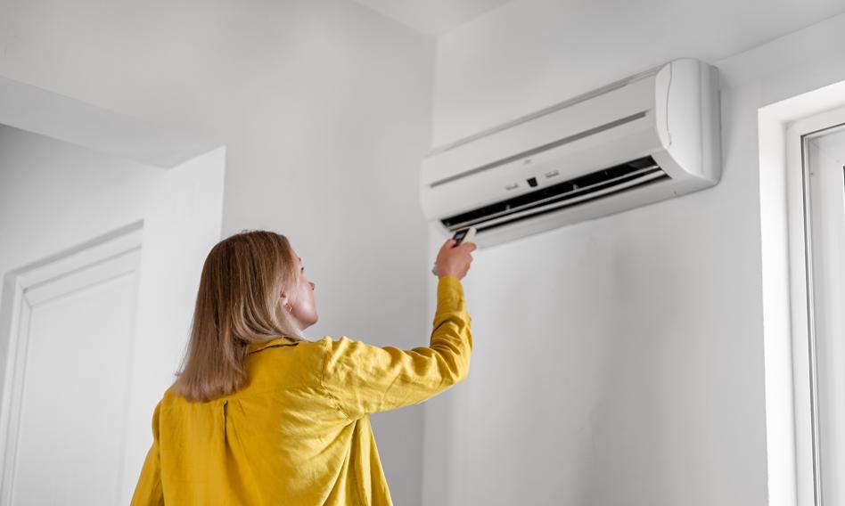 Kobieta obsługująca klimatyzację przy użyciu pilota